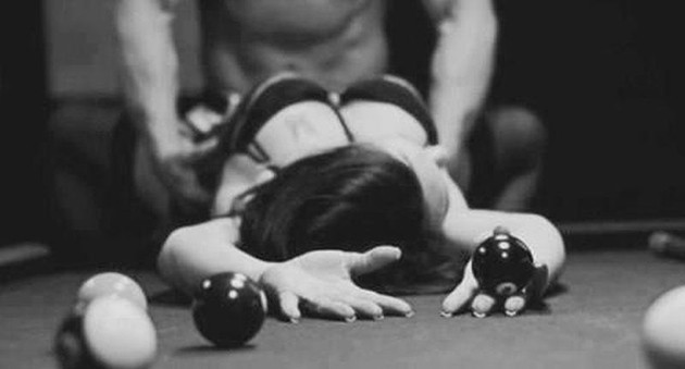 Swingers - Woman in lingerie lying on pool table with man holding her from the front